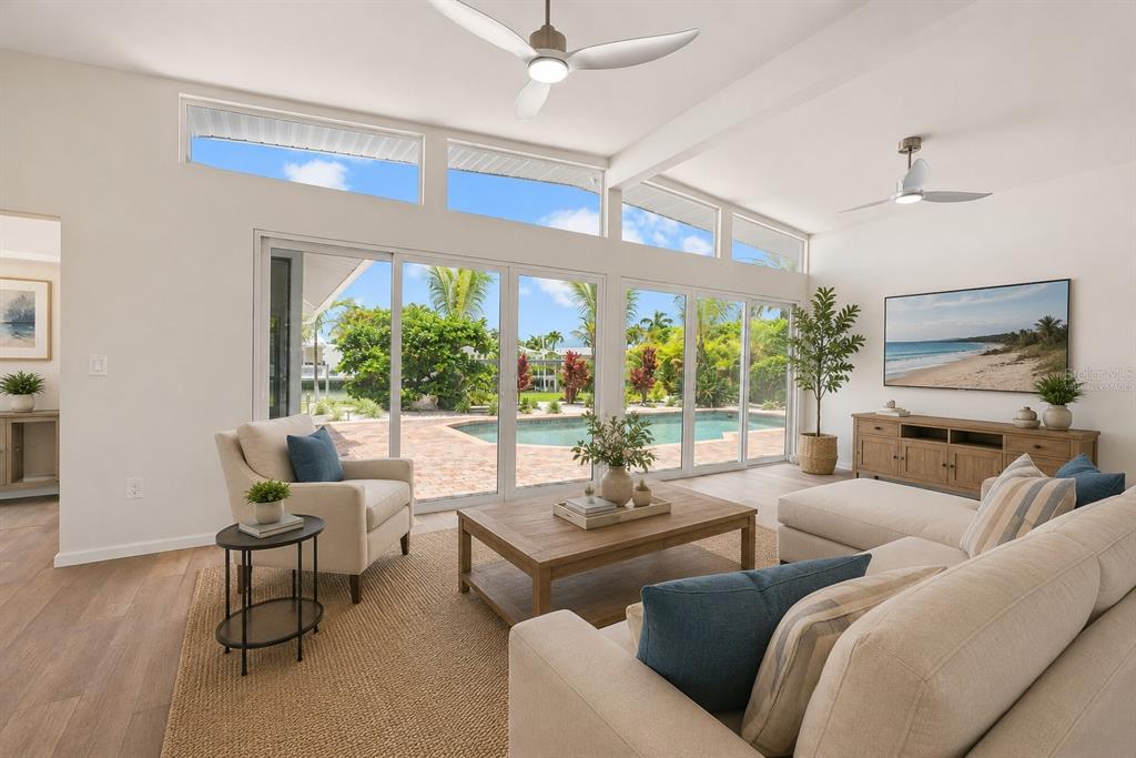 A bright living room features large sliding glass doors overlooking a pool and patio area — 528 KEY ROYALE DRIVE, HOLMES BEACH, FL