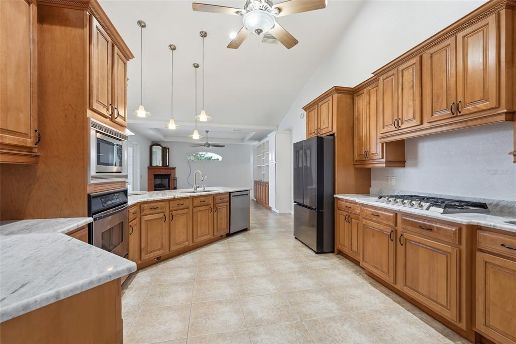 A kitchen features wood cabinets, marble countertops, stainless steel appliances, and tile flooring — 470 SPRING LAKE BOULEVARD NW, PORT CHARLOTTE, FL
