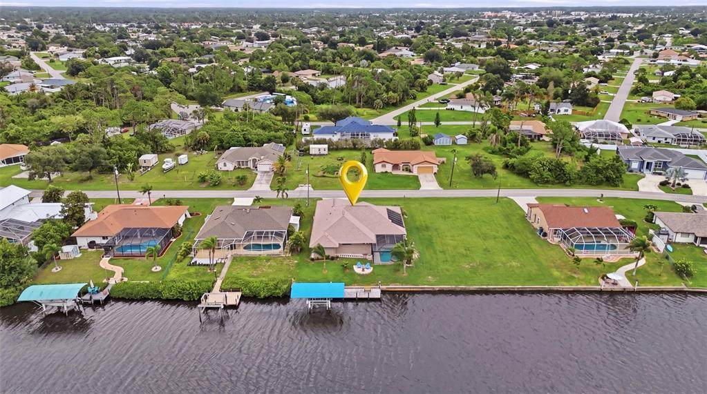 An aerial view shows a waterfront house with a pool and dock on a canal — 470 SPRING LAKE BOULEVARD NW, PORT CHARLOTTE, FL