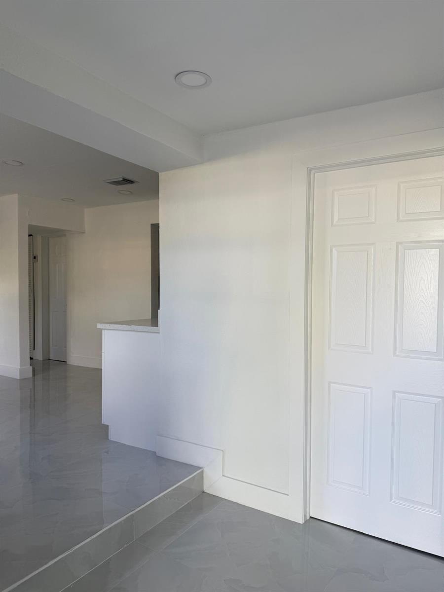 A white door stands next to a raised floor area with grey tile flooring — 4400 SW 36th Street, West Park FL 33023, WEST PARK, FL