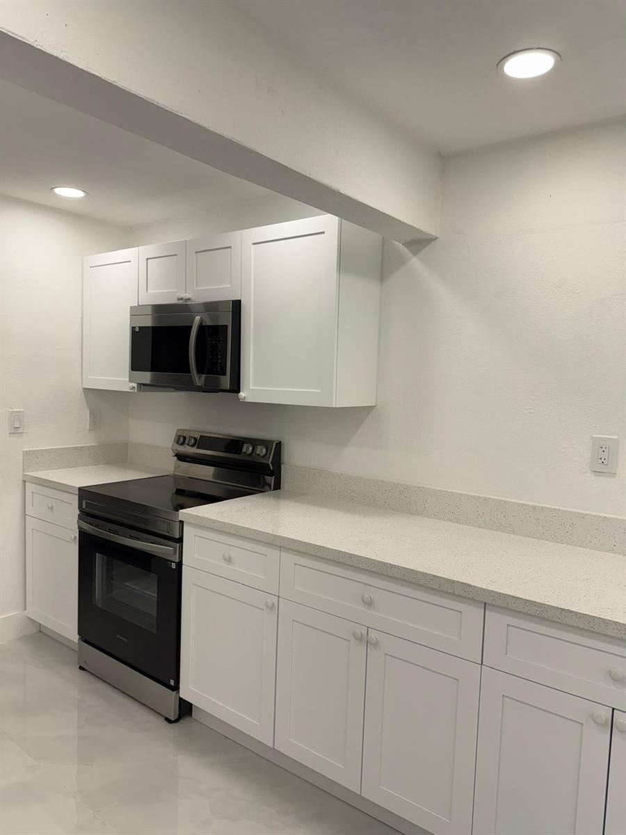 A kitchen features white shaker cabinets, stainless steel appliances, and light-colored quartz countertops — 4400 SW 36th Street, West Park FL 33023, WEST PARK, FL