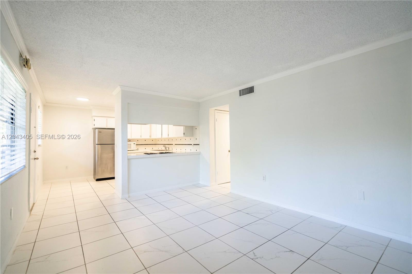 A kitchen with stainless steel appliances is visible from a tiled living area — 3265 Virginia St # 18, Miami FL 33133, MIAMI, FL