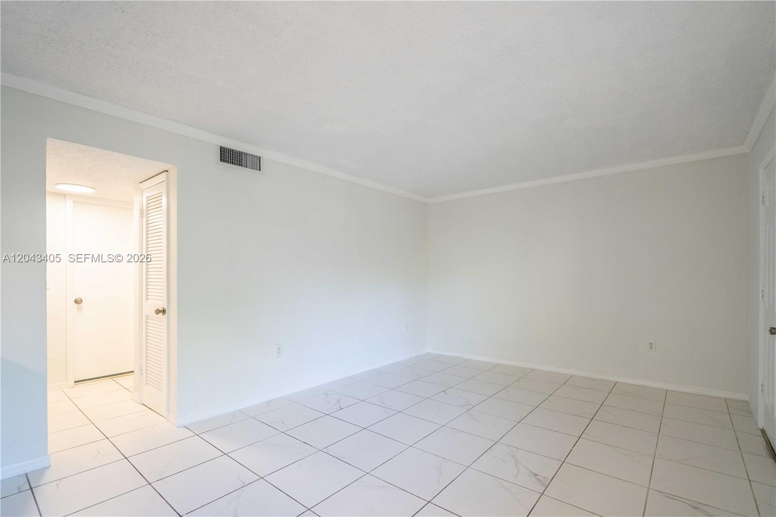 An empty room features white walls, a textured ceiling, and white marble-patterned tile flooring — 3265 Virginia St # 18, Miami FL 33133, MIAMI, FL