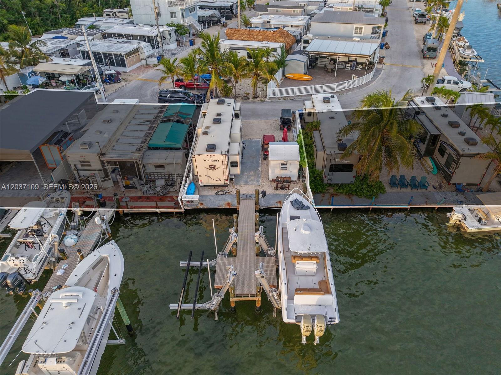An aerial view shows two RVs parked on waterfront lots with private boat docks — 325 Calusa St, Key Largo FL 33037, KEY LARGO, FL