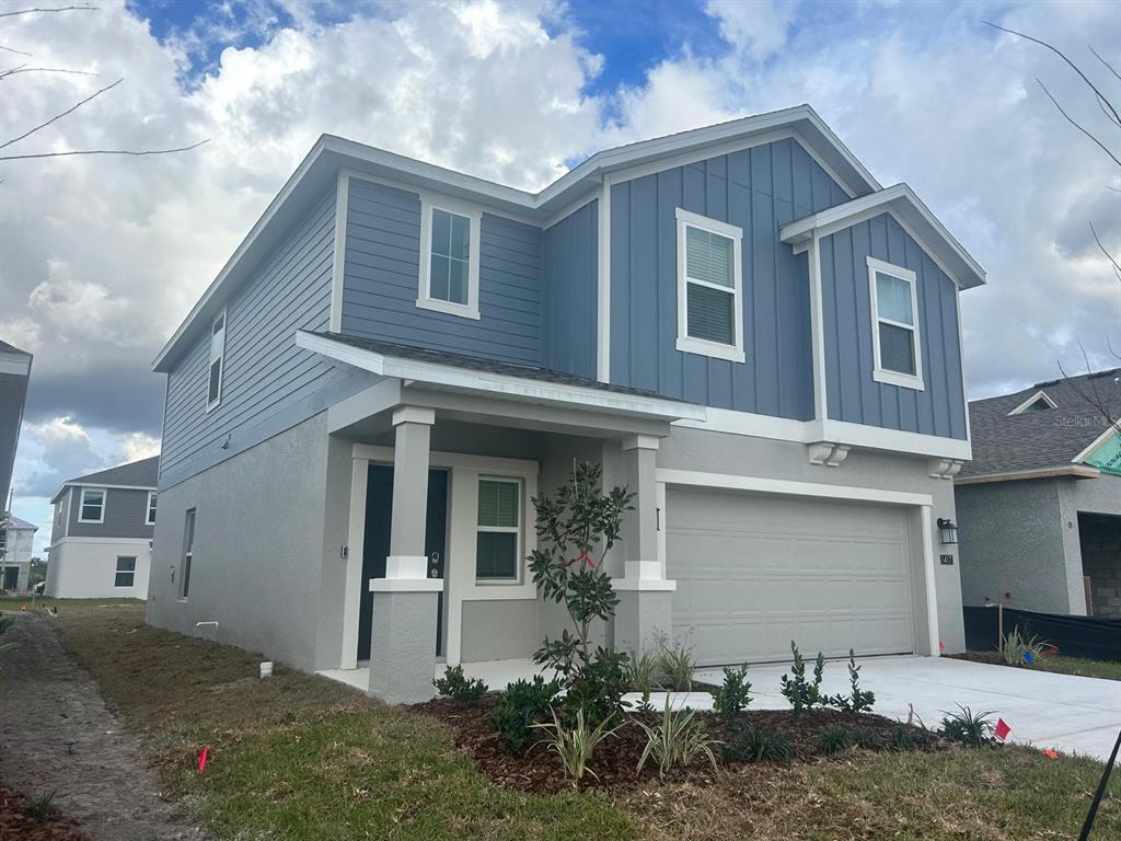 A two-story house with blue vertical siding, a gray stucco base, and a two-car garage — 1417 AUSTIN STREET, WINTER HAVEN, FL