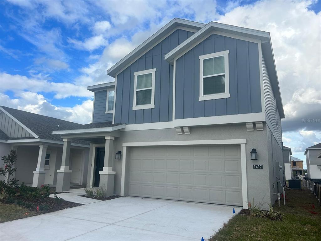 A two-story house with a gray garage, blue vertical siding, and a covered front porch — 1417 AUSTIN STREET, WINTER HAVEN, FL