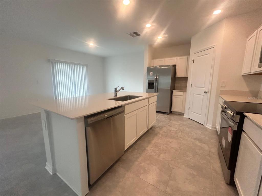 A kitchen features white cabinets, stainless steel appliances, a center island, and tile flooring — 1417 AUSTIN STREET, WINTER HAVEN, FL