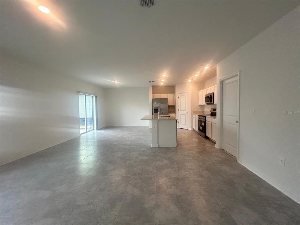 An open-concept kitchen and living area features white cabinetry, stainless appliances, and tile flooring — 1417 AUSTIN STREET, WINTER HAVEN, FL