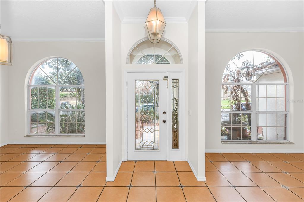 An entryway with tan tile floors, a white front door, and two arched windows — 1587 HUNTERS STAND RUN, OVIEDO, FL