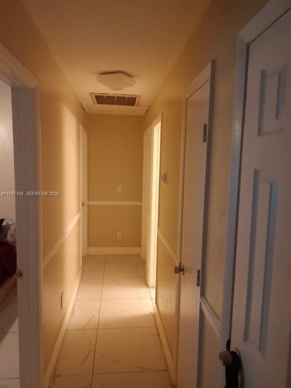 A narrow hallway with light-colored tile flooring, beige walls, and several white interior doors — 3917 4, Lehigh Acres FL 33971, LEHIGH ACRES, FL