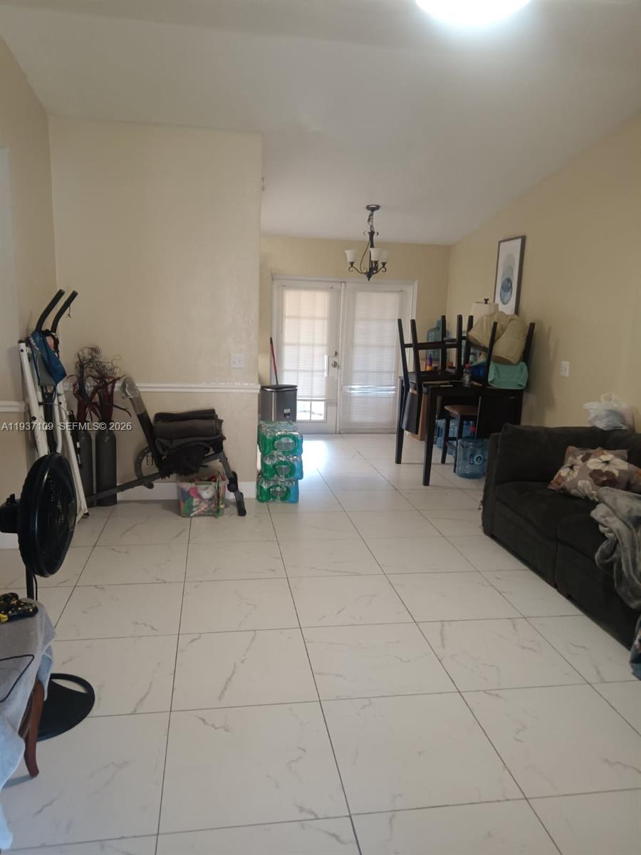 A living room with white tile flooring, a dark sofa, and a dining set — 3917 4, Lehigh Acres FL 33971, LEHIGH ACRES, FL