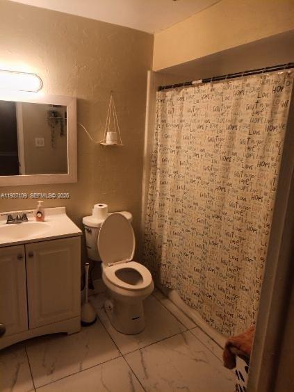A bathroom features a white vanity, a toilet, and a shower with a patterned curtain — 3917 4, Lehigh Acres FL 33971, LEHIGH ACRES, FL