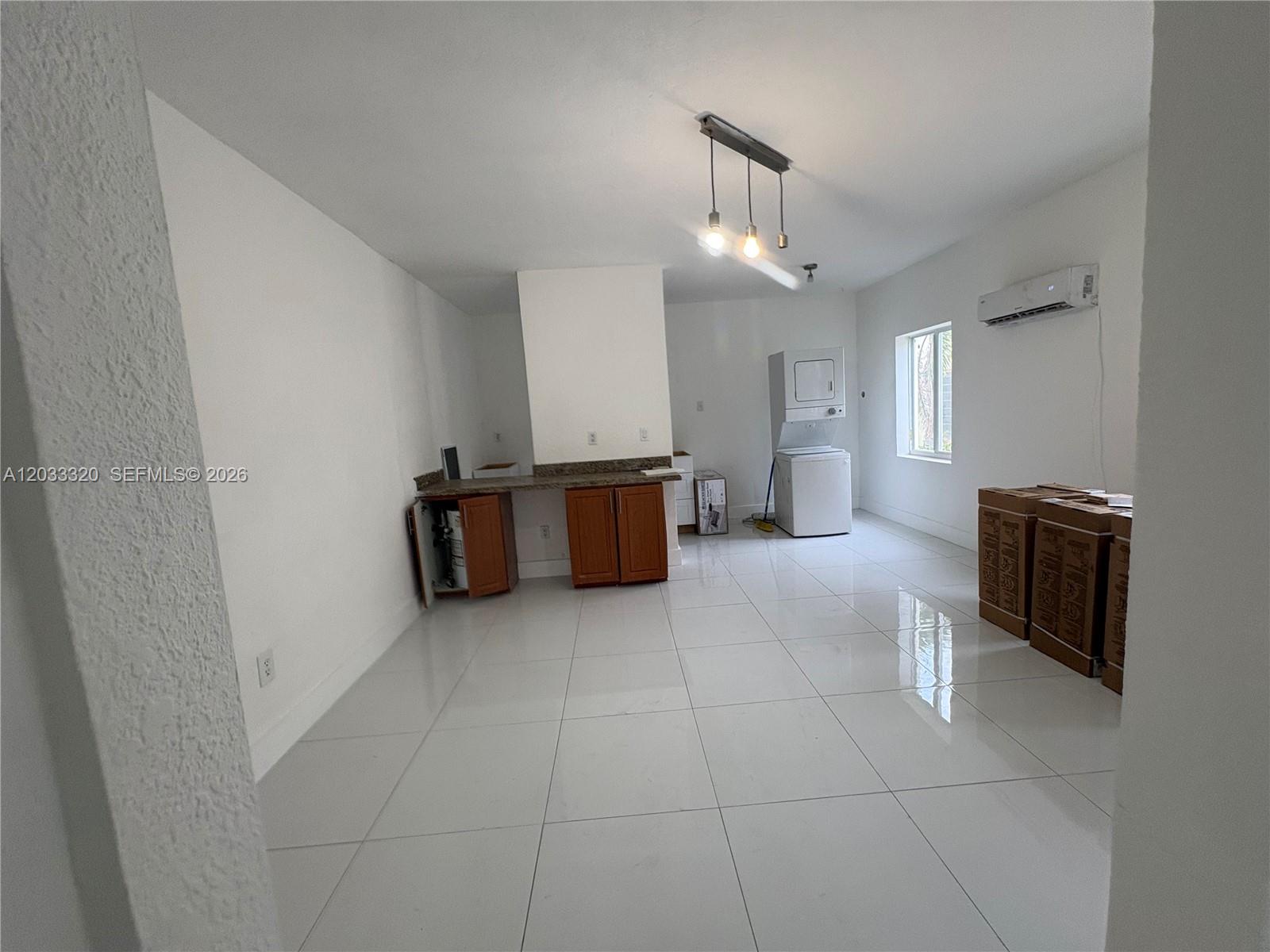 A room with white tile floors, a small kitchenette, and a stacked washer and dryer — 7920 Harding Ave # 8, Miami Beach FL 33141, MIAMI BEACH, FL