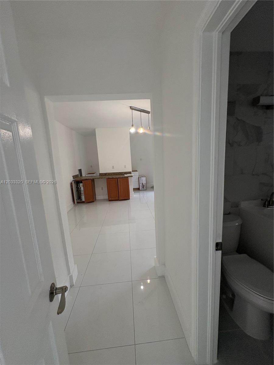 A view from a doorway shows a tiled hallway leading to a kitchen with cabinets — 7920 Harding Ave # 8, Miami Beach FL 33141, MIAMI BEACH, FL