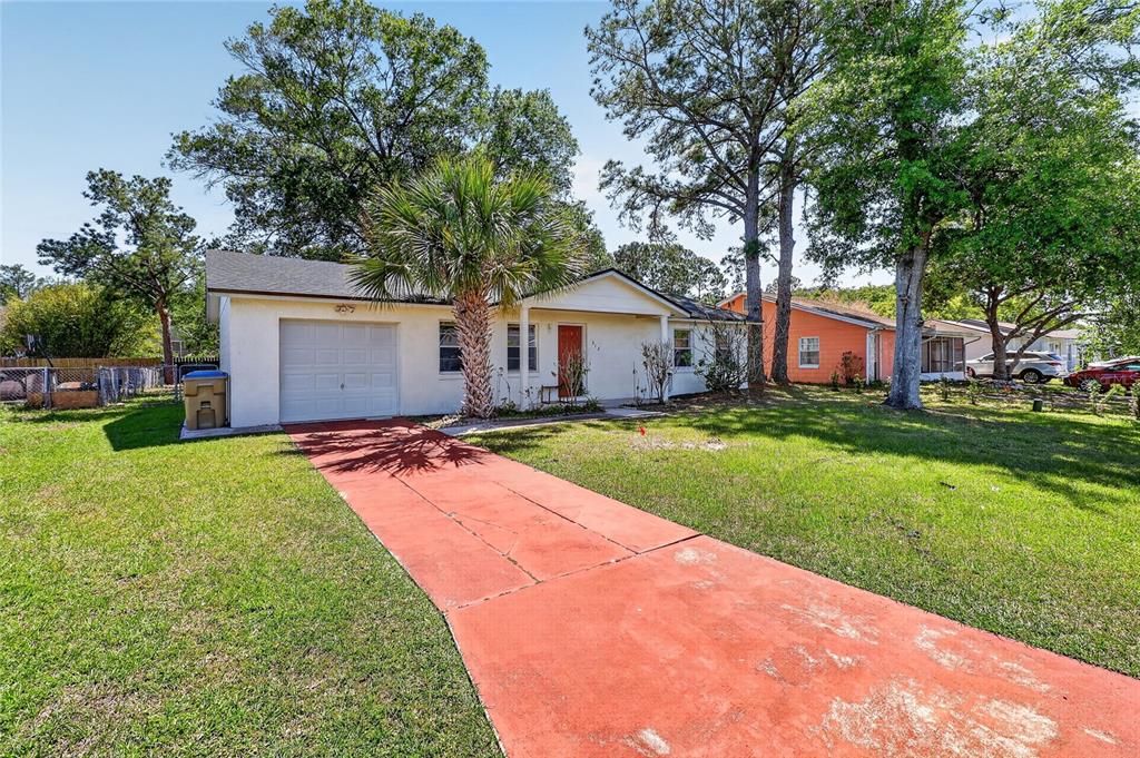 A single-story house with a red driveway, a white garage, and a palm tree — 312 LA PAZ DRIVE, KISSIMMEE, FL