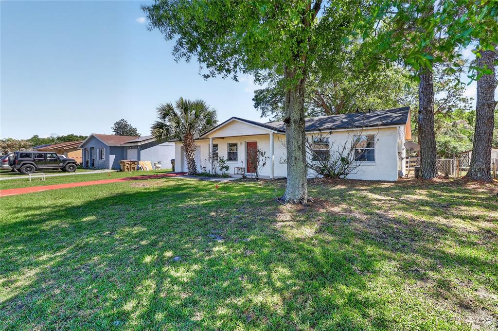 A single-story white house with a red front door sits on a grassy lawn — 312 LA PAZ DRIVE, KISSIMMEE, FL
