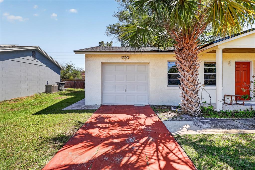 A single-story house with a white stucco exterior, a red front door, and a palm tree — 312 LA PAZ DRIVE, KISSIMMEE, FL