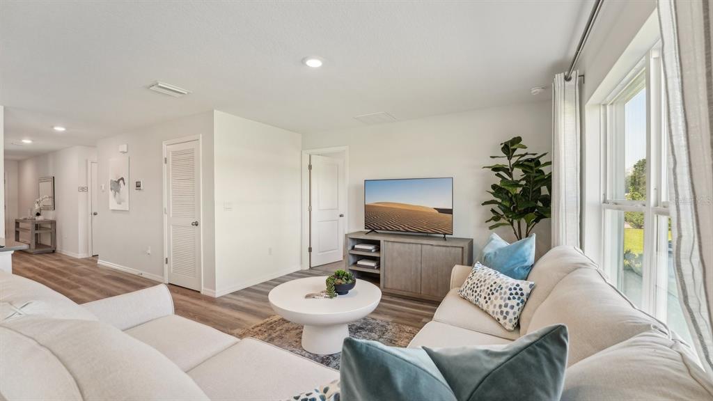 A living room features a light-colored sectional sofa, a round coffee table, and a television — 1118 WILD CLOVER WAY, PLANT CITY, FL