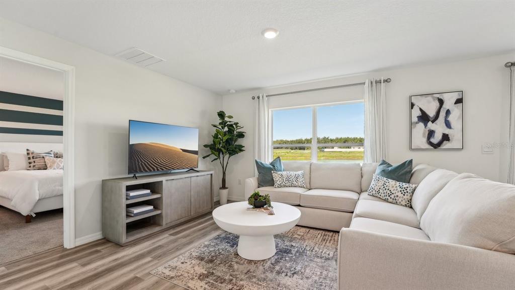 A living room features a sectional sofa, a television on a console, and a window — 1118 WILD CLOVER WAY, PLANT CITY, FL
