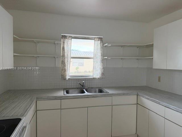 A kitchen features white cabinets, open shelving, a double sink, and a window with curtains — 2128 Roosevelt St # 3, Hollywood FL 33020, HOLLYWOOD, FL