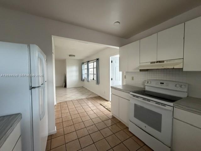 A kitchen with white cabinets and appliances opens into a tiled dining area — 2128 Roosevelt St # 3, Hollywood FL 33020, HOLLYWOOD, FL
