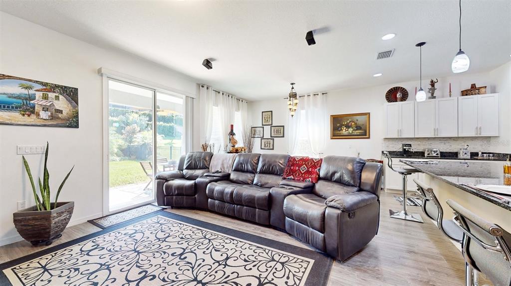 An open-concept living room features a dark leather sectional, a patterned rug, and a kitchen — 626 CONSERVATION BOULEVARD, GROVELAND, FL