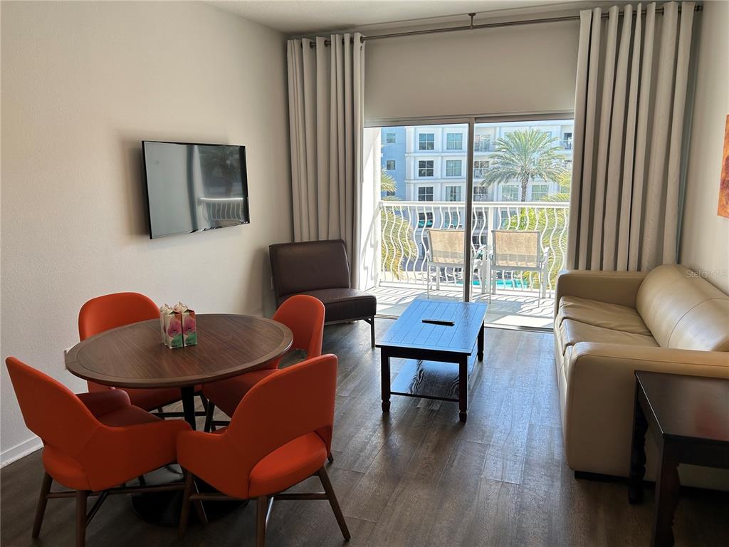 A living and dining area features orange chairs, a wooden table, and a beige sofa — 225 CELEBRATION PLACE UNIT 446, KISSIMMEE, FL