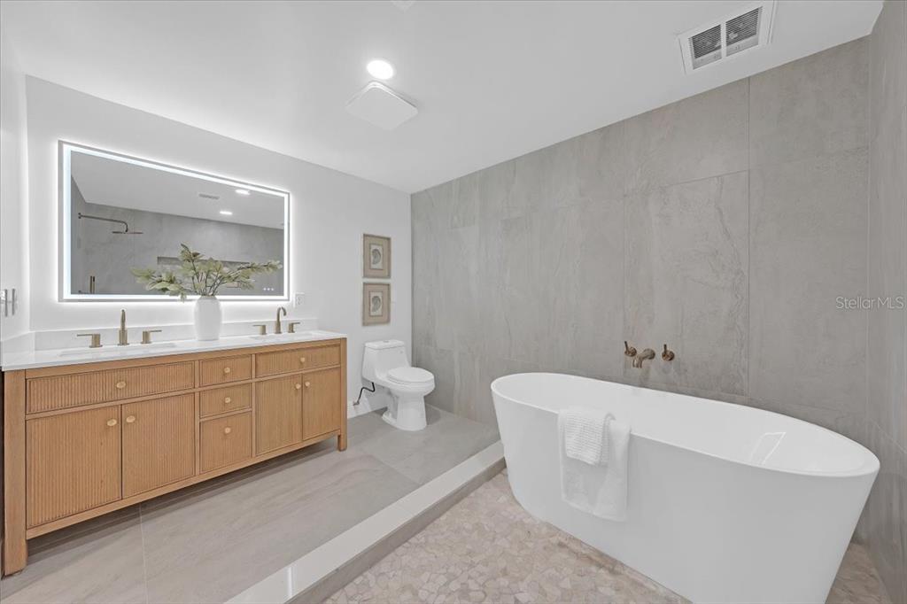 A modern bathroom features a wooden vanity, a freestanding tub, and gray tile walls — 1110 12TH STREET N, ST PETERSBURG, FL