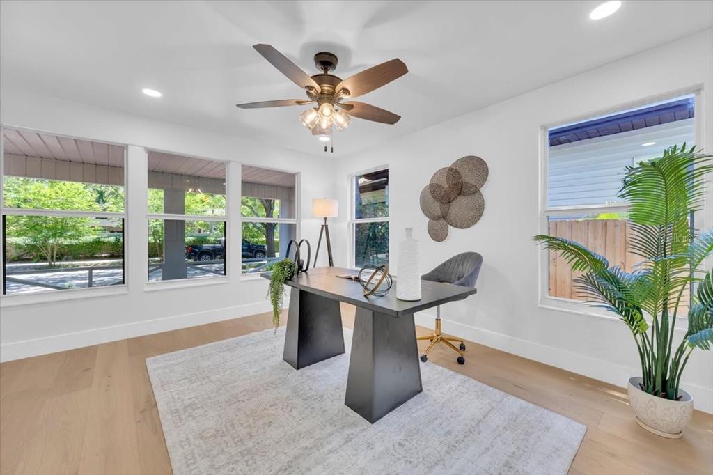 A bright home office features a dark desk, a ceiling fan, and large windows — 1110 12TH STREET N, ST PETERSBURG, FL