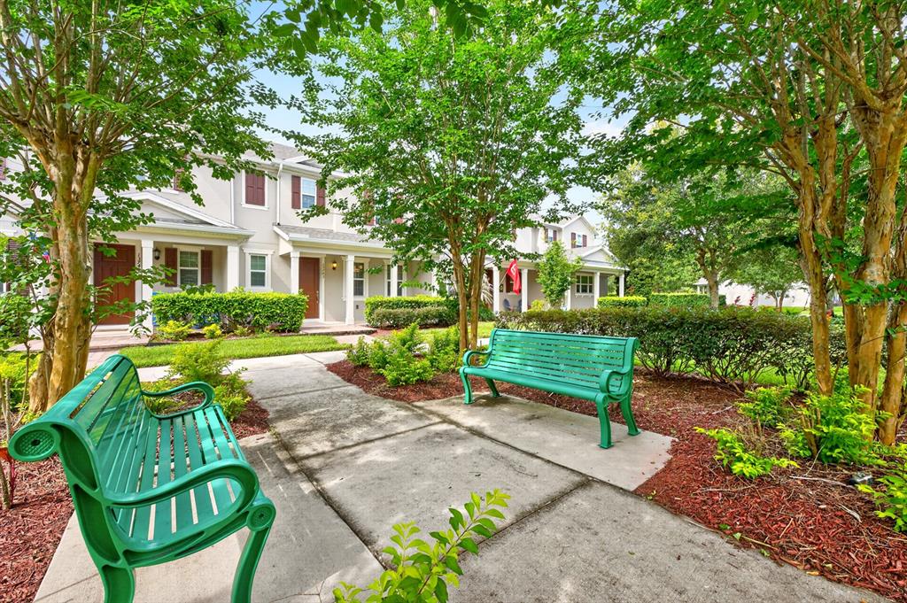 Two green benches sit on a concrete path in front of townhouses and trees — 13743 CALERA ALLEY, WINDERMERE, FL