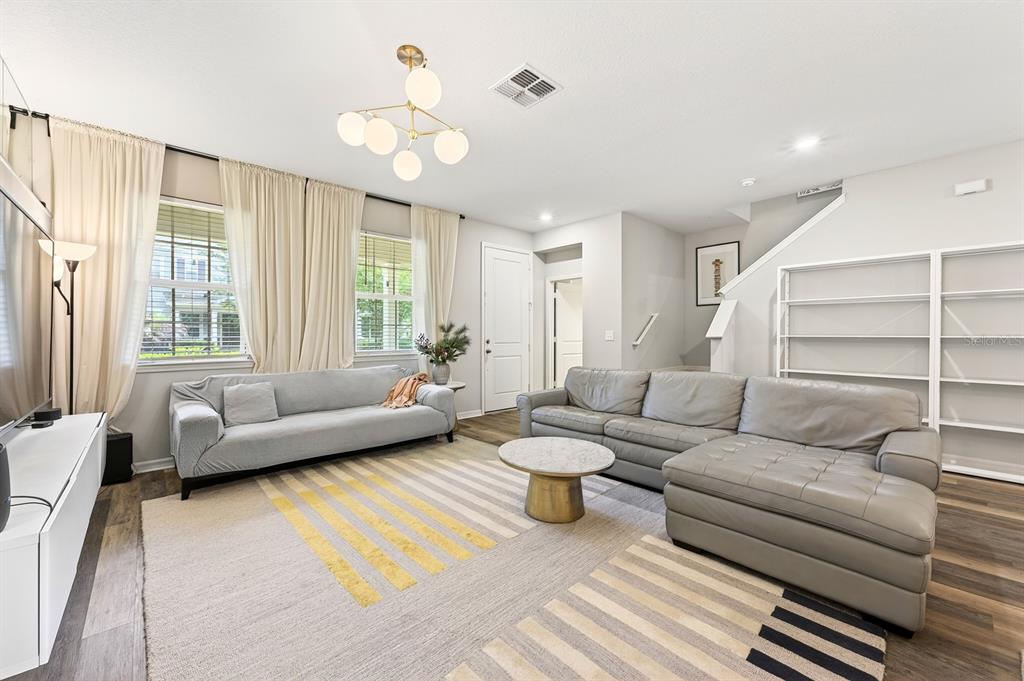 A living room features two gray sofas, a patterned area rug, and white built-in shelving — 13743 CALERA ALLEY, WINDERMERE, FL