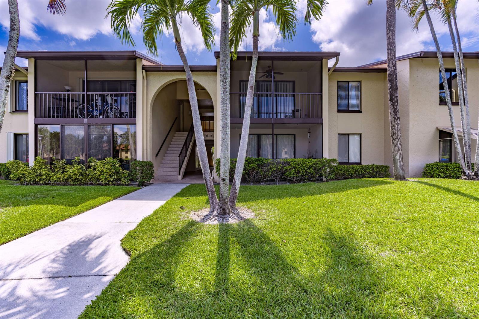 A two-story apartment building with a screened balcony, arched entryway, and palm trees — 610 Sea Pine Way # B2, FL 33415, FL