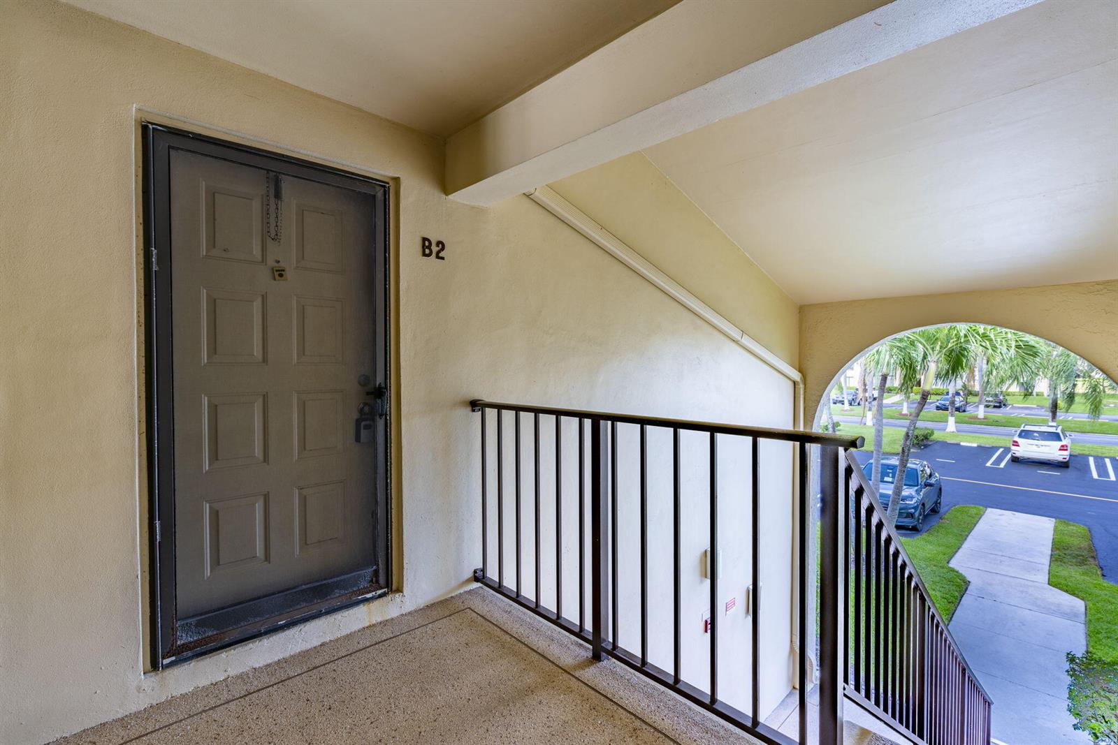 An exterior view of a second-floor apartment entrance labeled B2 with a metal railing — 610 Sea Pine Way # B2, FL 33415, FL