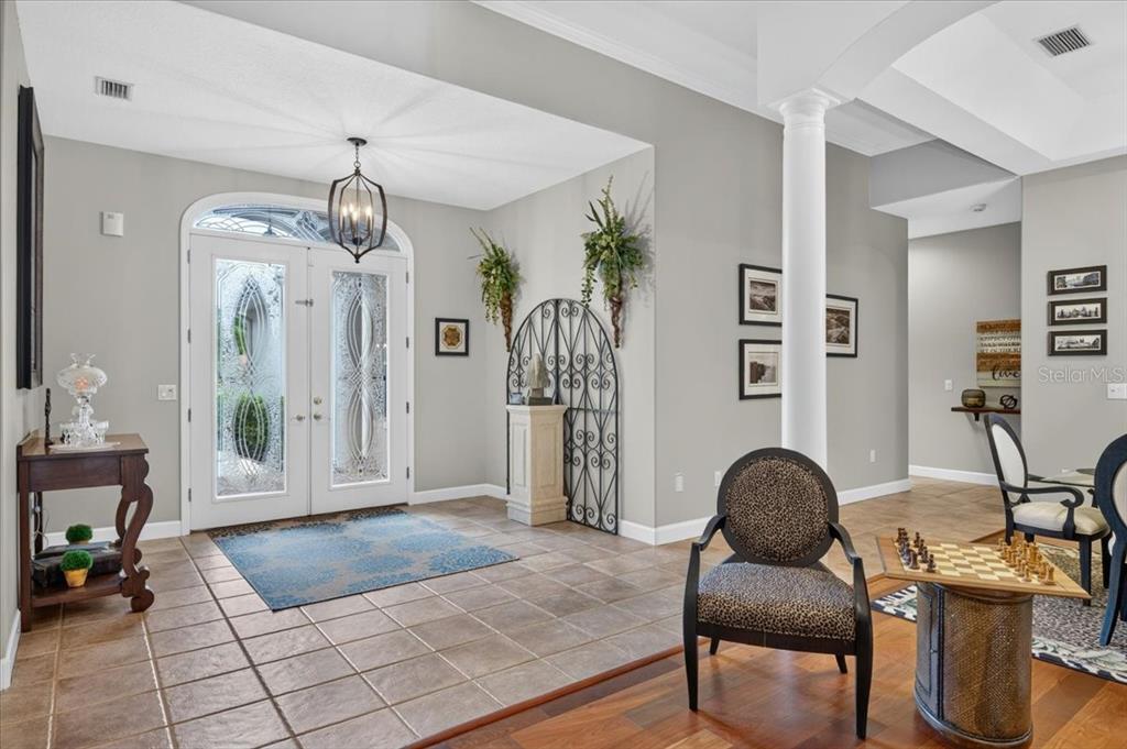 A spacious foyer features tile flooring, a double front door, and a central white column — 3874 CRESCENT COVE PLACE, TARPON SPRINGS, FL