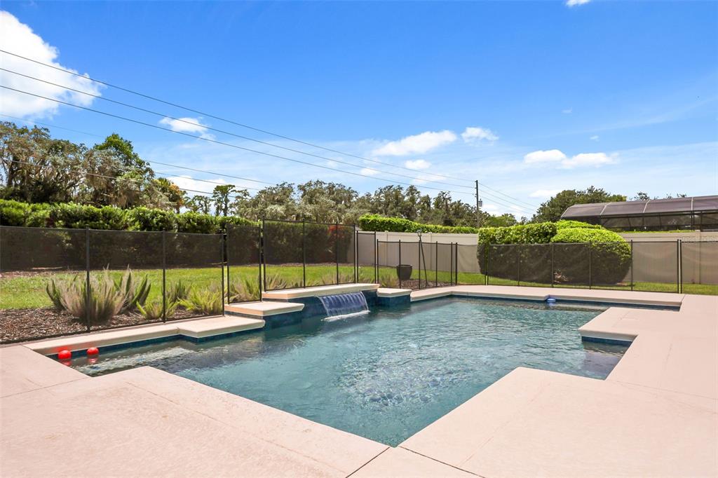 A rectangular swimming pool with a water feature sits in a fenced backyard — 17112 GUILFORD COURT, ORLANDO, FL