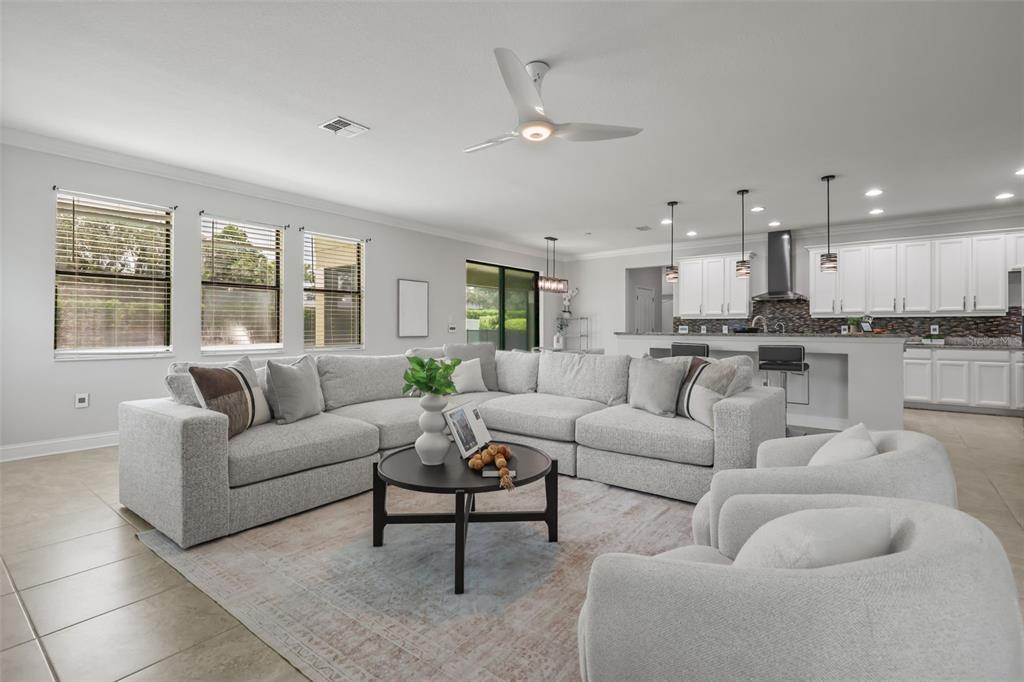 A spacious open-concept living room features a large sectional sofa, round coffee table, and kitchen — 17112 GUILFORD COURT, ORLANDO, FL