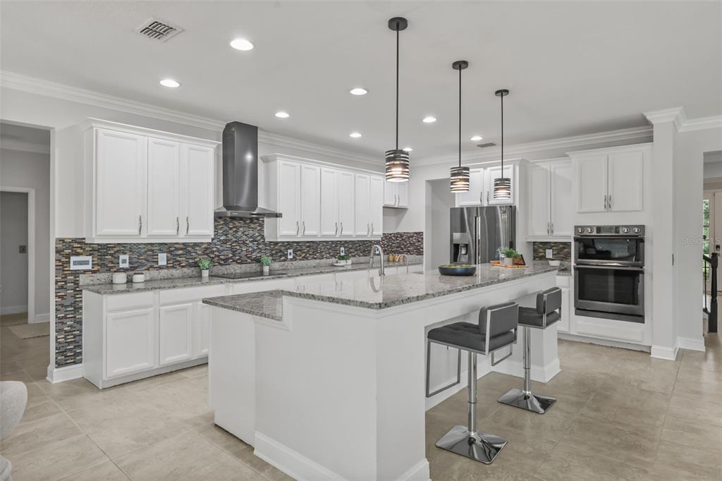 A modern kitchen features white cabinets, granite countertops, a tiled backsplash, and a center island — 17112 GUILFORD COURT, ORLANDO, FL