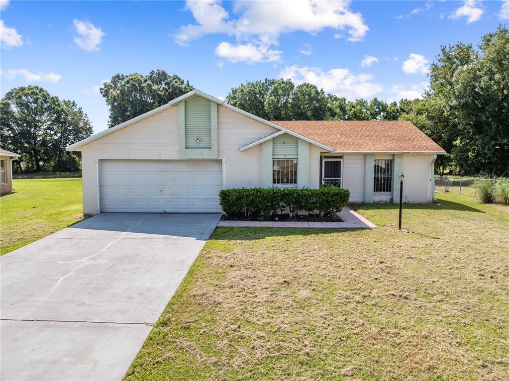 A single-story house with a beige exterior, brown roof, and a concrete driveway — 743 DROMEDARY DRIVE, POINCIANA, FL