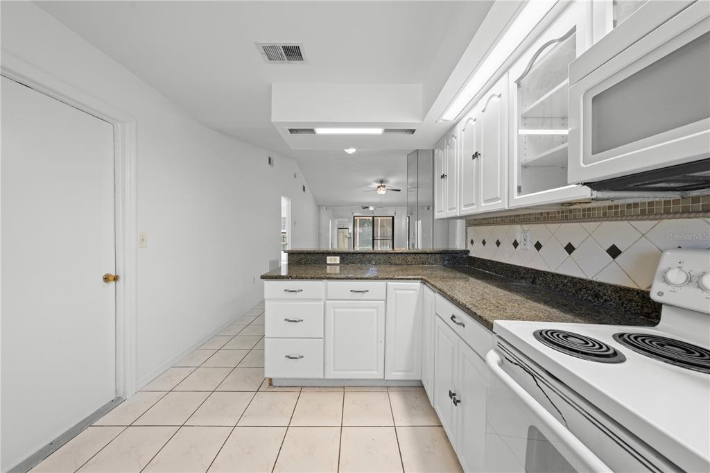 A kitchen with white cabinets, granite countertops, and tile flooring — 743 DROMEDARY DRIVE, POINCIANA, FL