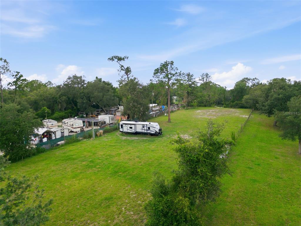 An aerial view shows a grassy lot with several recreational vehicles parked near trees — 32402 PINE ROAD, EUSTIS, FL