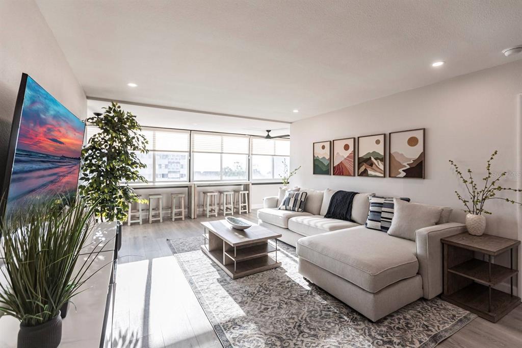 A modern living room features a sectional sofa, a coffee table, and a window-side bar — 1125 W PEPPERTREE DRIVE UNIT 402, SARASOTA, FL