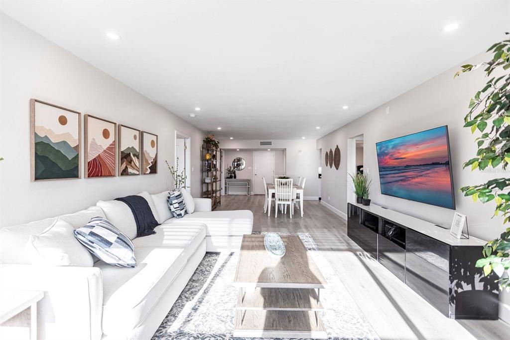A bright living room features a white sectional sofa, a wood coffee table, and a television — 1125 W PEPPERTREE DRIVE UNIT 402, SARASOTA, FL