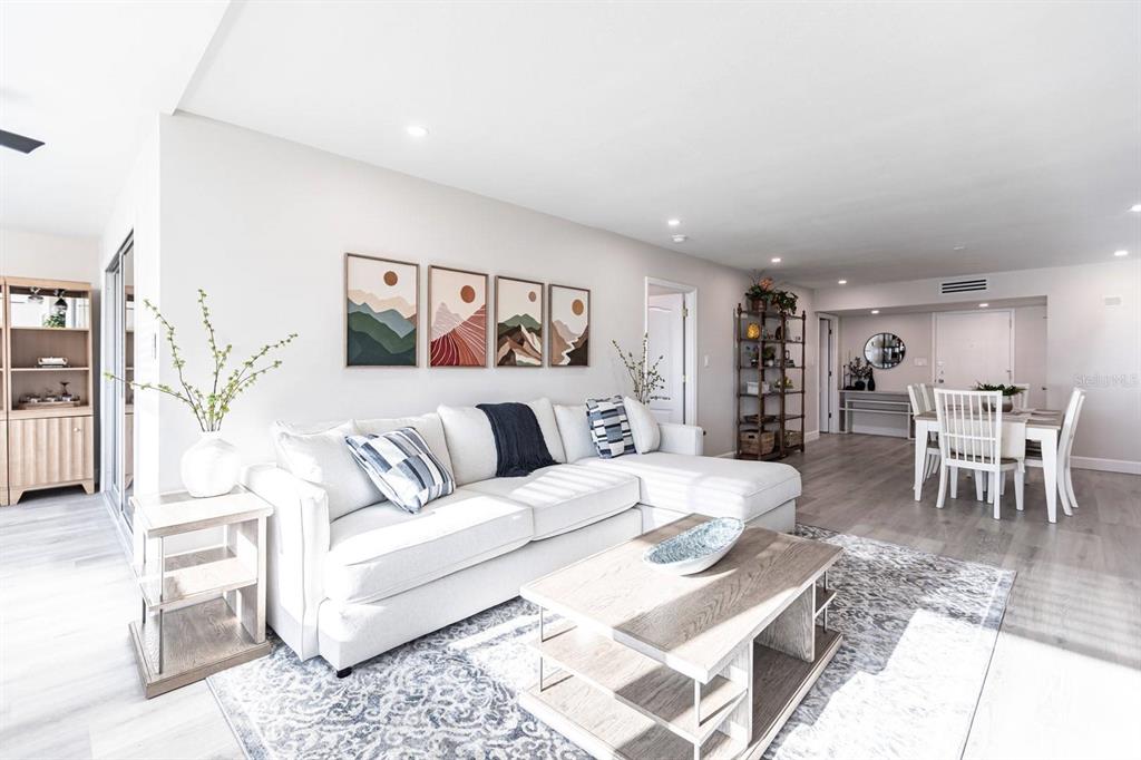 A bright living room features a white sectional sofa, a wooden coffee table, and wall art — 1125 W PEPPERTREE DRIVE UNIT 402, SARASOTA, FL