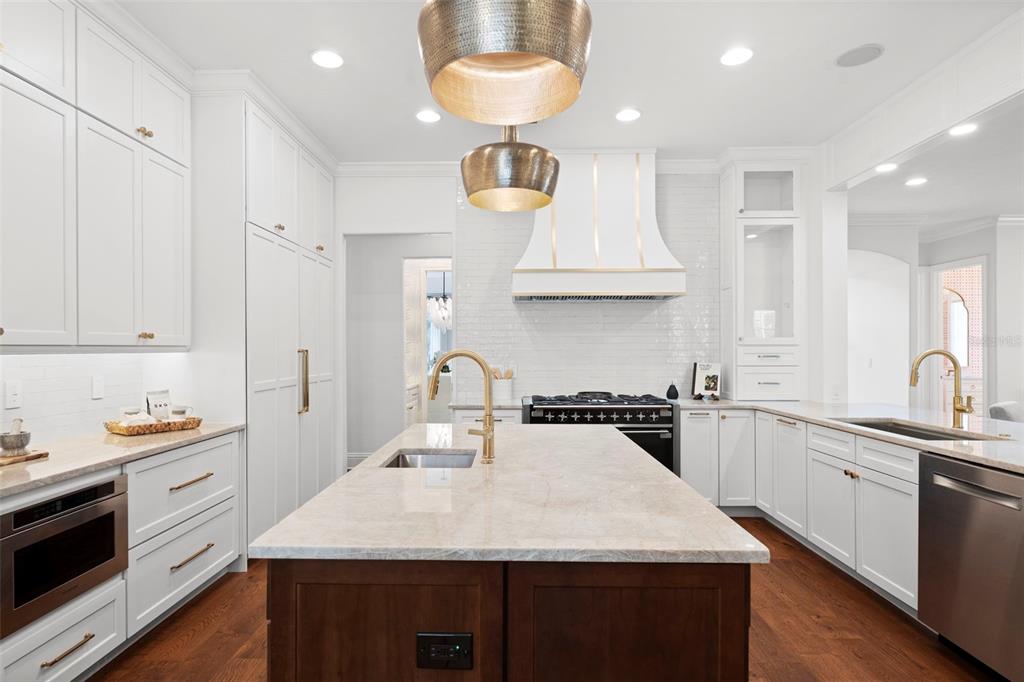 A kitchen features white cabinetry, a dark wood island, gold hardware, and stainless steel appliances — 4406 W AZEELE STREET, TAMPA, FL