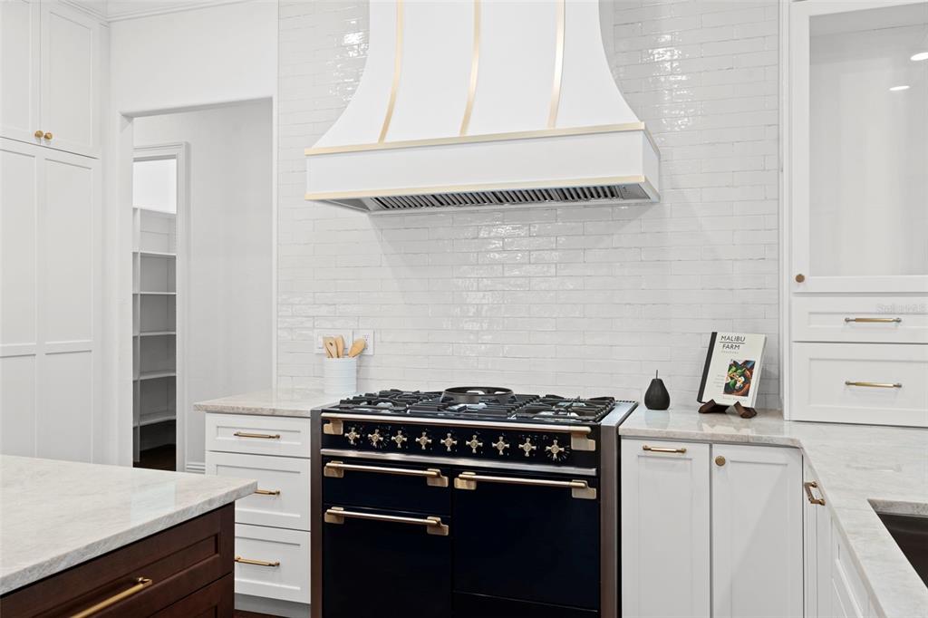 A kitchen features a black range, a white custom hood, and white subway tile backsplash — 4406 W AZEELE STREET, TAMPA, FL
