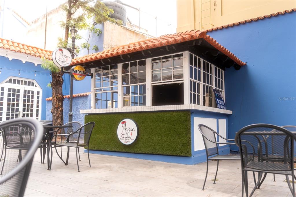 An outdoor kiosk with a tiled roof and green turf siding sits in a blue courtyard — 1 C. ISABEL MUÑOZ RIVERA, PONCE, PR