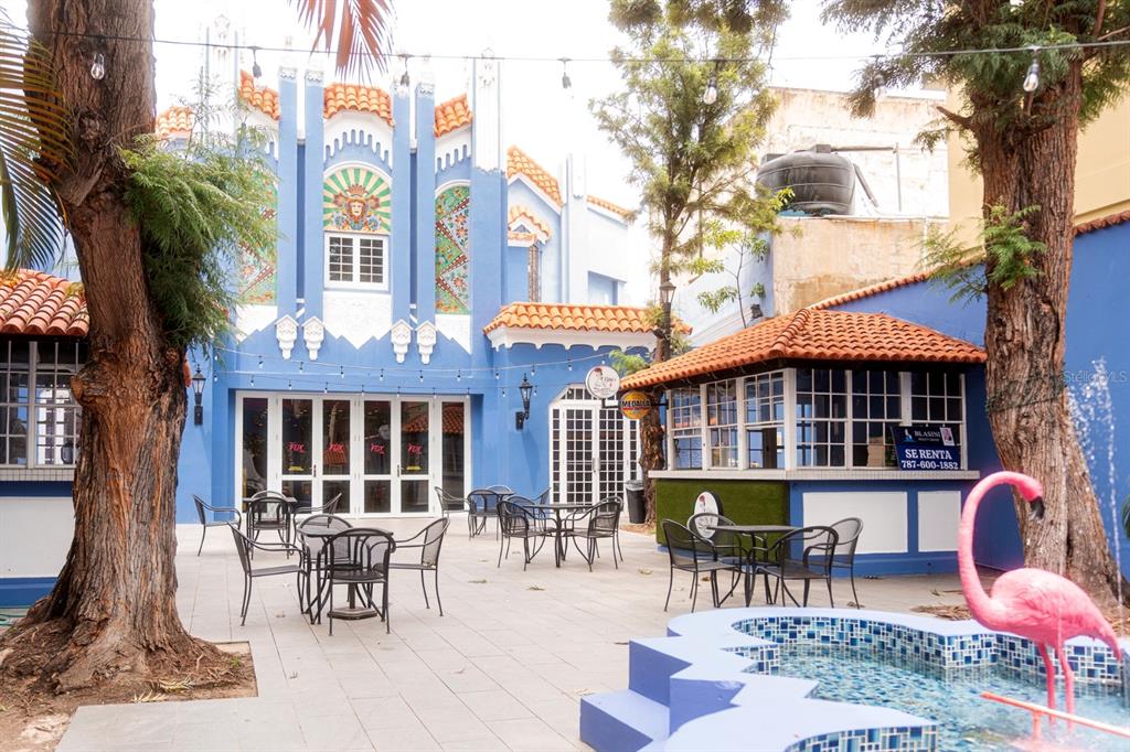 An outdoor patio features a blue building, a tiled fountain, and a pink flamingo statue — 1 C. ISABEL MUÑOZ RIVERA, PONCE, PR