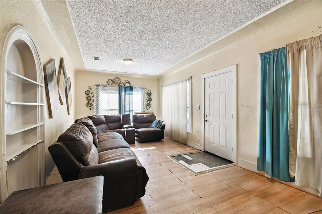 A living room features a brown sectional sofa, tile flooring, and a white arched built-in shelf — 3417 E LAKE AVENUE, TAMPA, FL