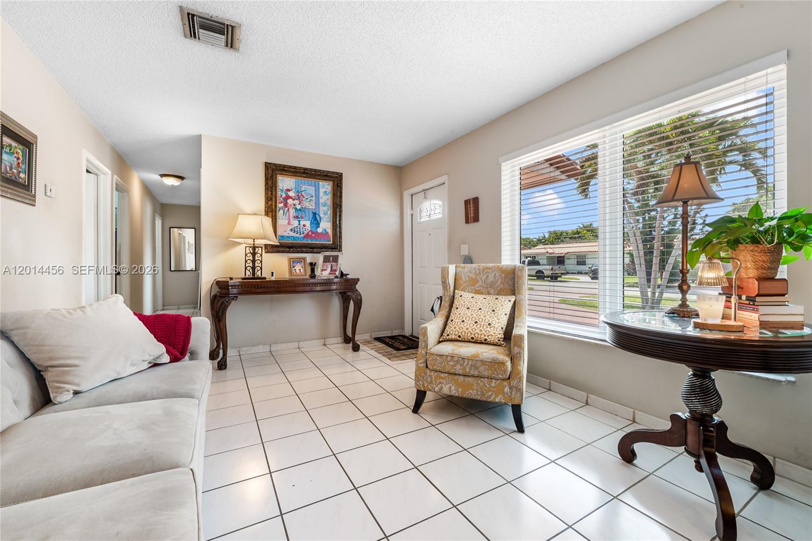 A living room features white tile floors, a patterned armchair, and a wooden console table — 10315 SW 26th Ter, Miami FL 33165, MIAMI, FL
