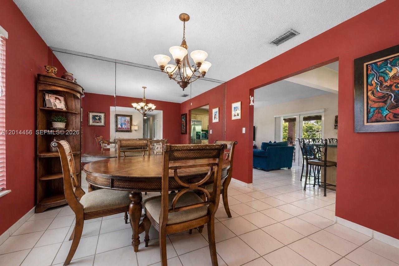 A dining room features red walls, a round wooden table, and a mirrored accent wall — 10315 SW 26th Ter, Miami FL 33165, MIAMI, FL